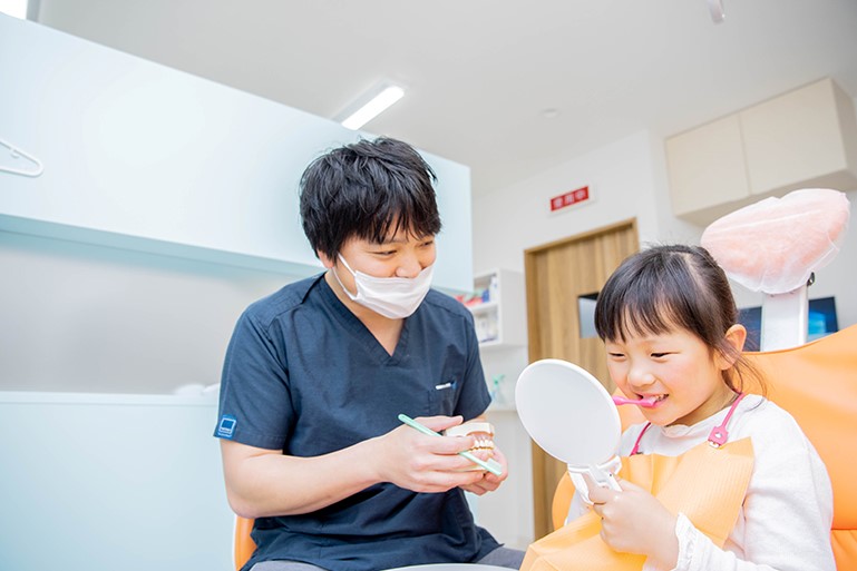 歯科医師が子どもに歯磨き指導をしている