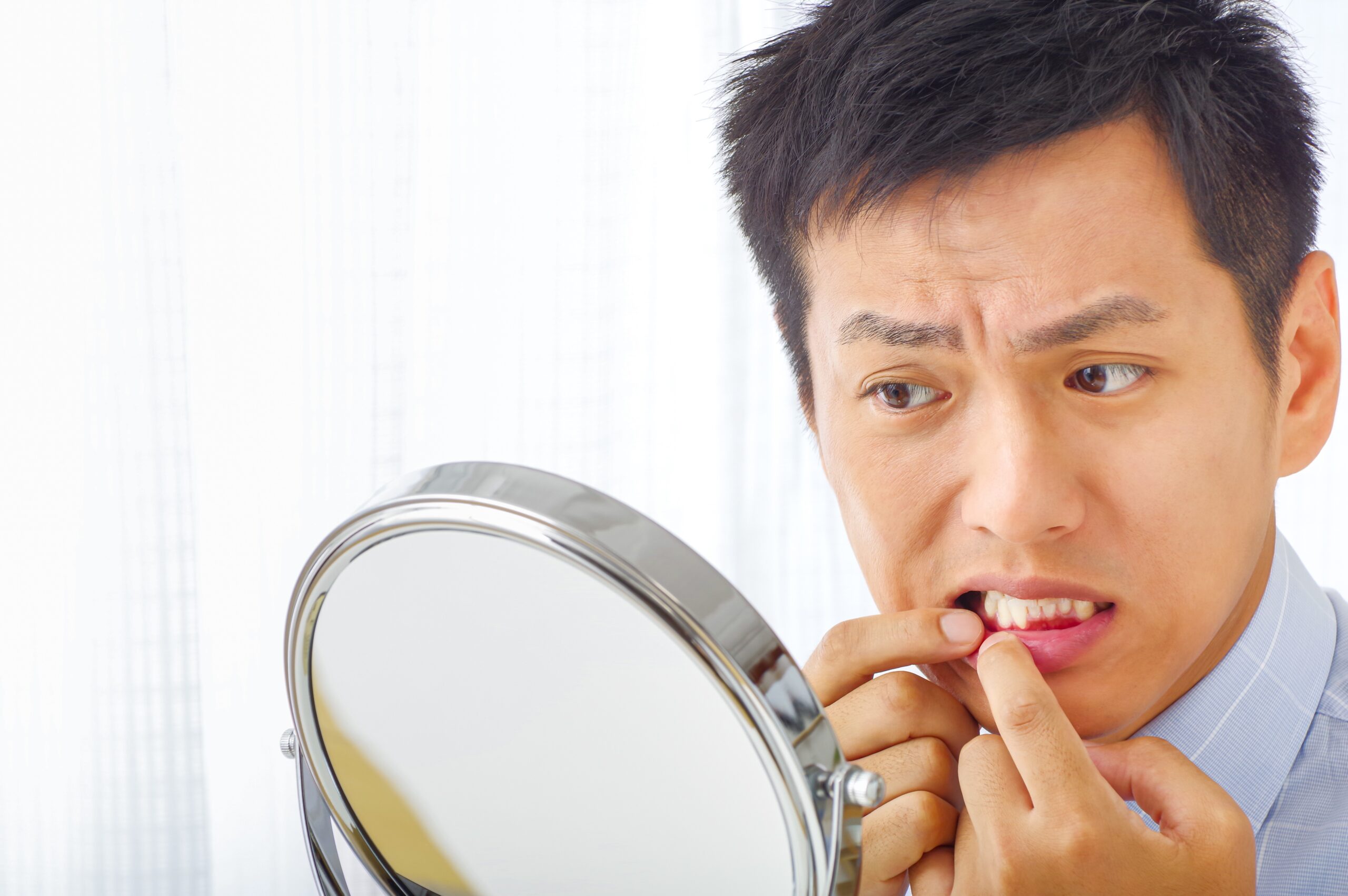 鏡で歯を確認する男性